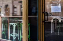 Wejście do lokalu, na drzwiach przywieszona kartka z napisem zamknięte do odwołania #zostań w domu