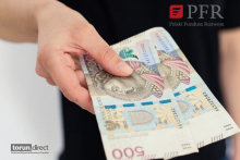 Zdjęcie przedstawia osobę trzymającą dwa banknoty 500 zł  i logotyp PFR