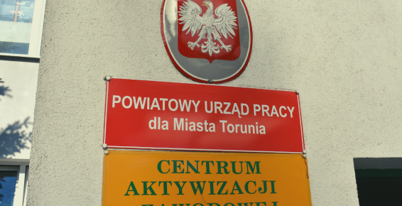 Polskie godło i szyldy wiszące przed wejściem do Powiatowego Urzędu Pracy dla Miasta Torunia przy ulicy Mazowieckiej w Toruniu